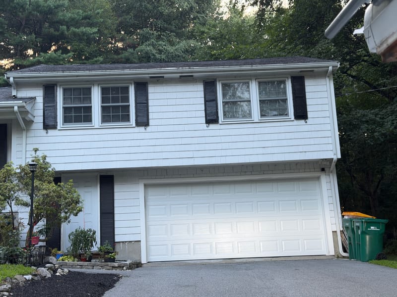 Front of a white split-level in Acton, MA after its new insulated double garage door went in
