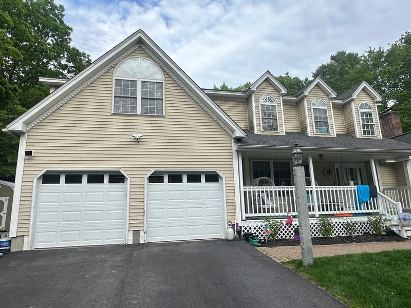 Two new white garage doors with windows on a yellow two-car garage