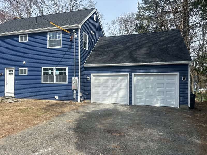 Navy house and two-car garage with two new white raised-panel garage doors